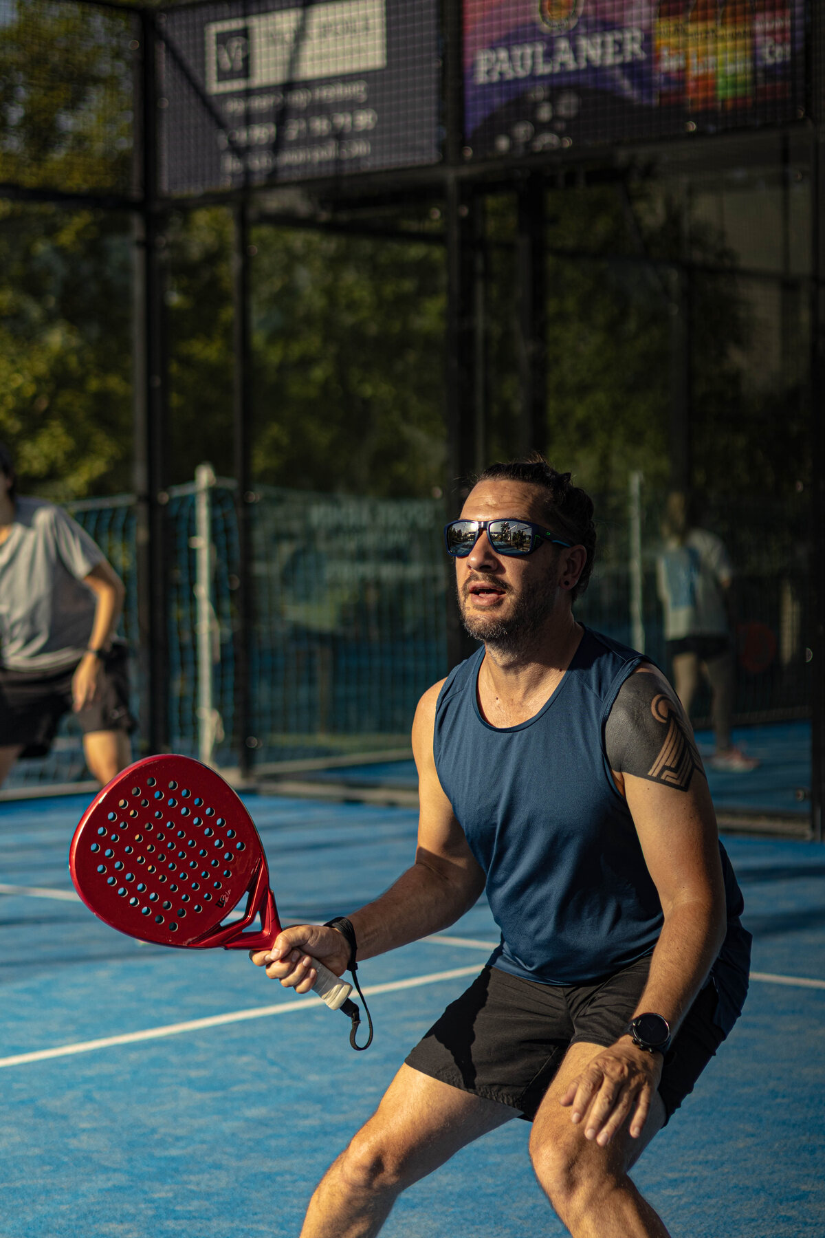 Padelspieler mit rotem Schläger auf dem Court